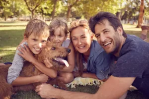 Family with dog smiling in park representing HelpMate trusted services
